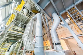 Manufacturing factory, wide-focus lens Down up view of modern operational plant with grey pipes and ladders heavy industry machinery metalworking workshop concept.