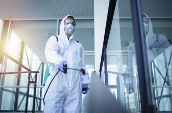 Person in white chemical protection suit doing disinfection of public areas to stop spreading highly contagious corona virus. Person in white chemical protection suit doing disinfection of public areas to stop spreading highly contagious corona virus.